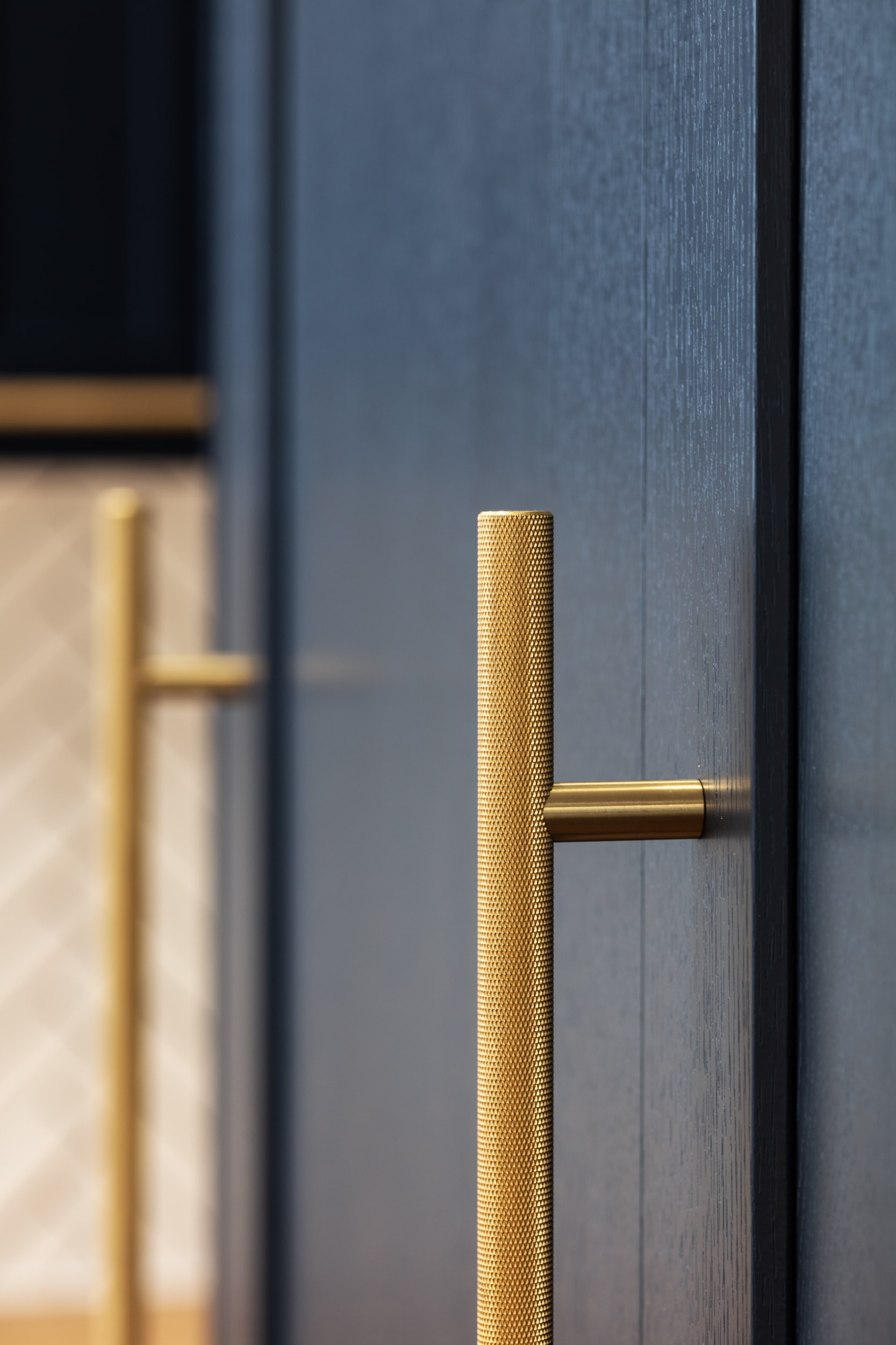 Close-up of a textured gold door handle against a dark wooden cabinet surface.