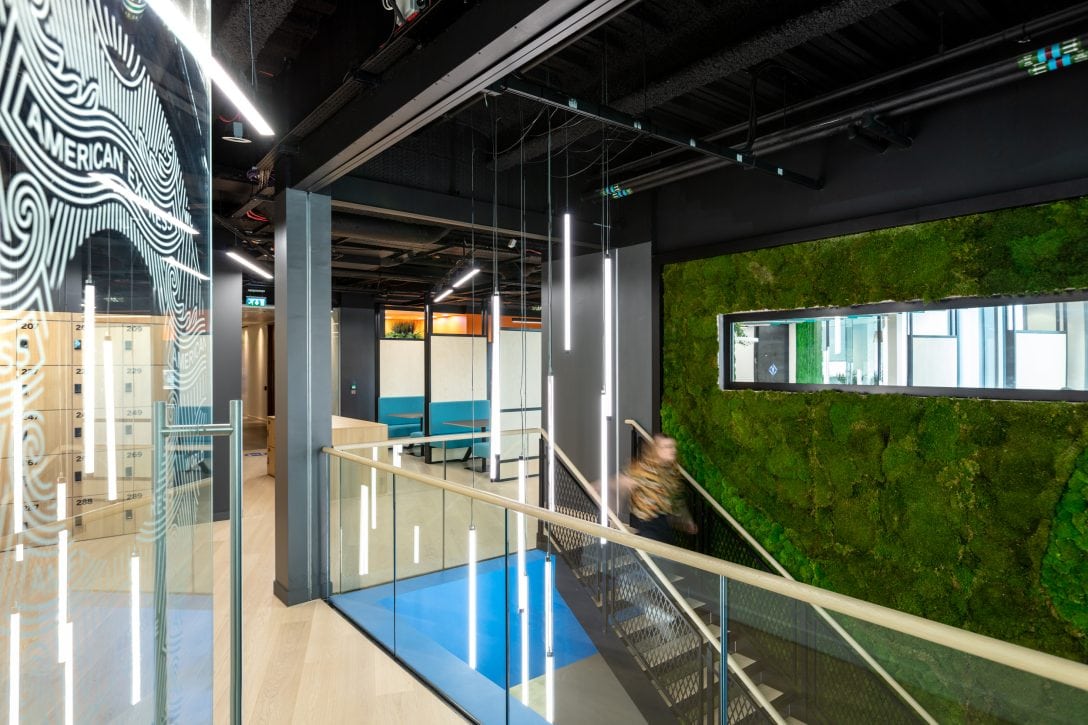 Image shows a woman walking down a staircase inside the hub office for a global corporate travel agent. 