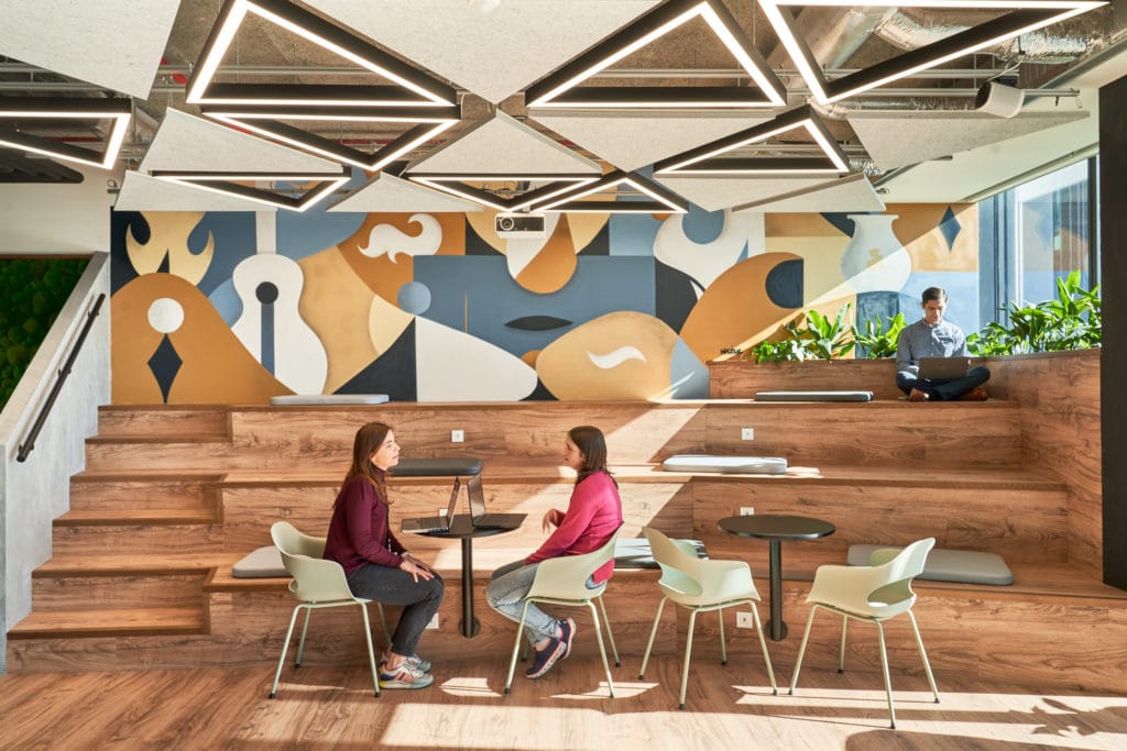 Employees working and collaborating on bleacher-style seating in the workplace.