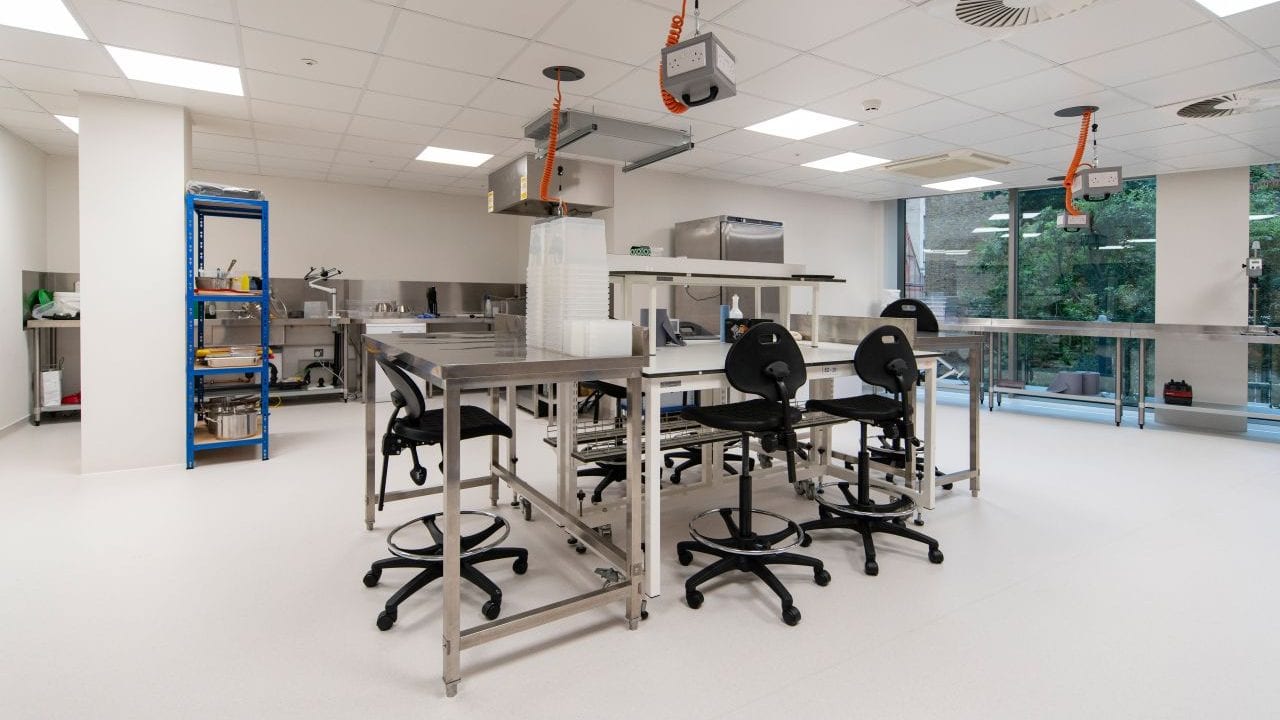 Inside a research and development laboratory designed by AIS, a bench is in the middle of the room surrounded by science equipment. 