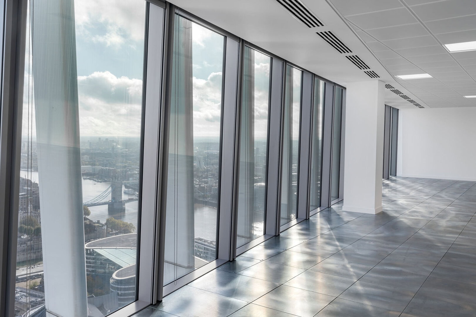 Interior view of a modern office space with large glass windows overlooking a cityscape and river.