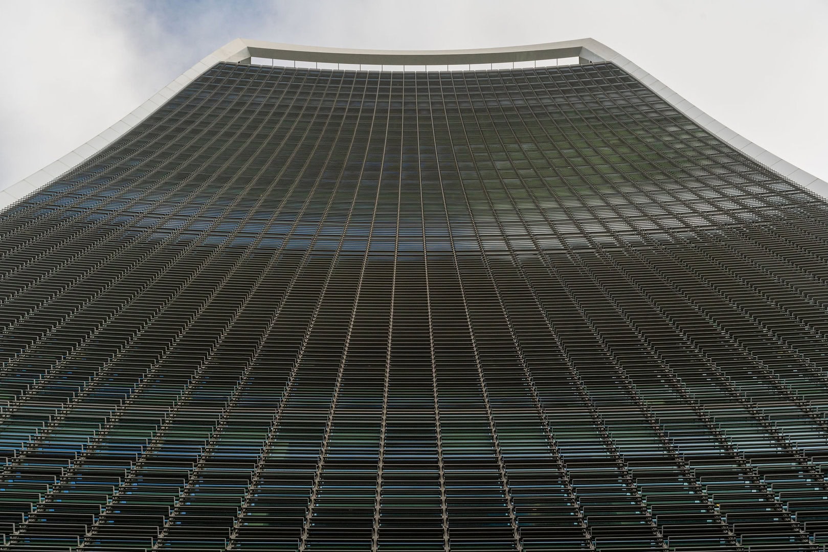 View of the curved glass facade of 20 Fenchurch Street, showcasing its distinctive architectural design from a low angle.