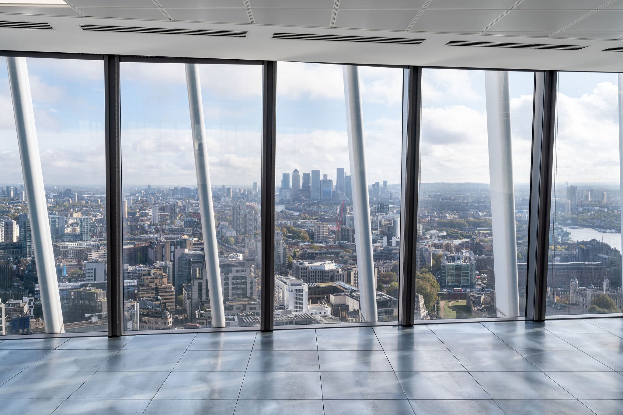 Panoramic view of London from the interior of 20 Fenchurch Street, showcasing the skyline and surrounding buildings through large glass windows.