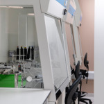 Laboratory workspace featuring pipettes, equipment, and empty chairs in a clean, modern environment.