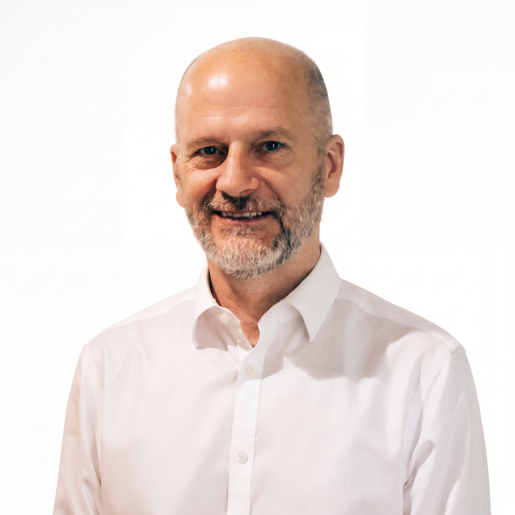 Man with a beard and bald head smiling, wearing a white button-up shirt against a light background.