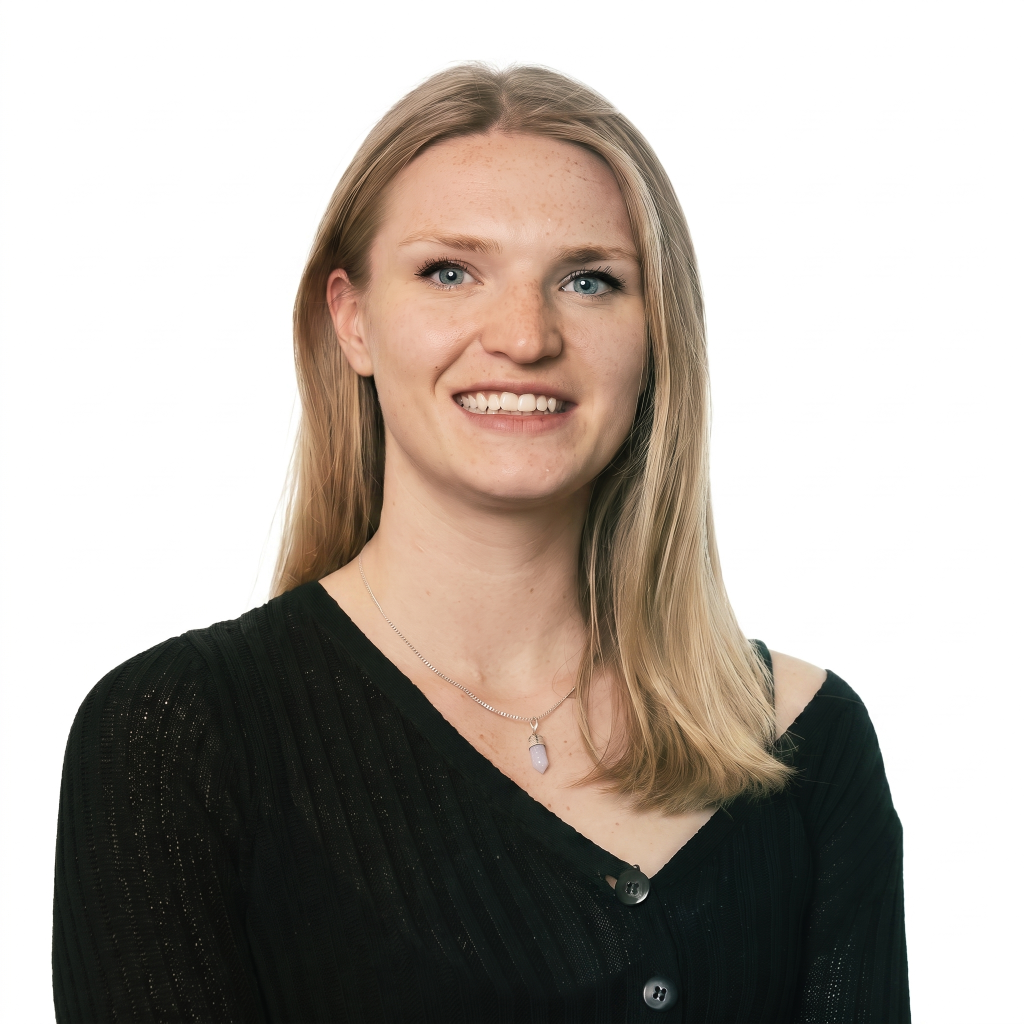 Smiling young woman with long blonde hair, wearing a black sweater and a necklace, against a white background.