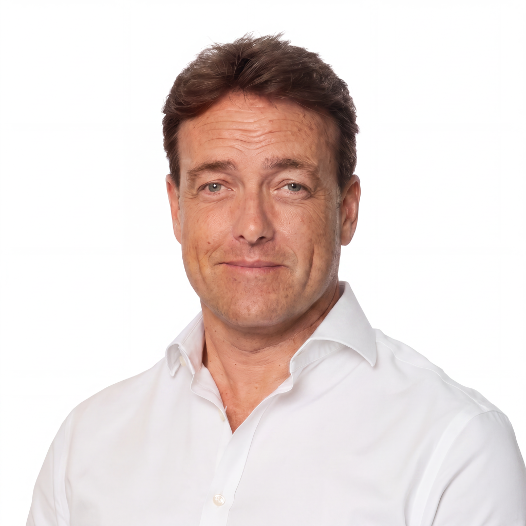 Man with short brown hair and a slight smile, wearing a white collared shirt, against a plain white background.
