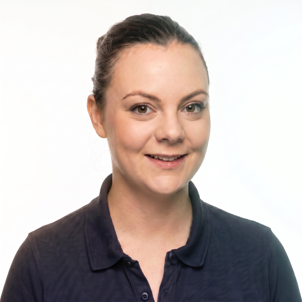Portrait of a woman with brown hair, wearing a dark polo shirt, smiling against a light background.