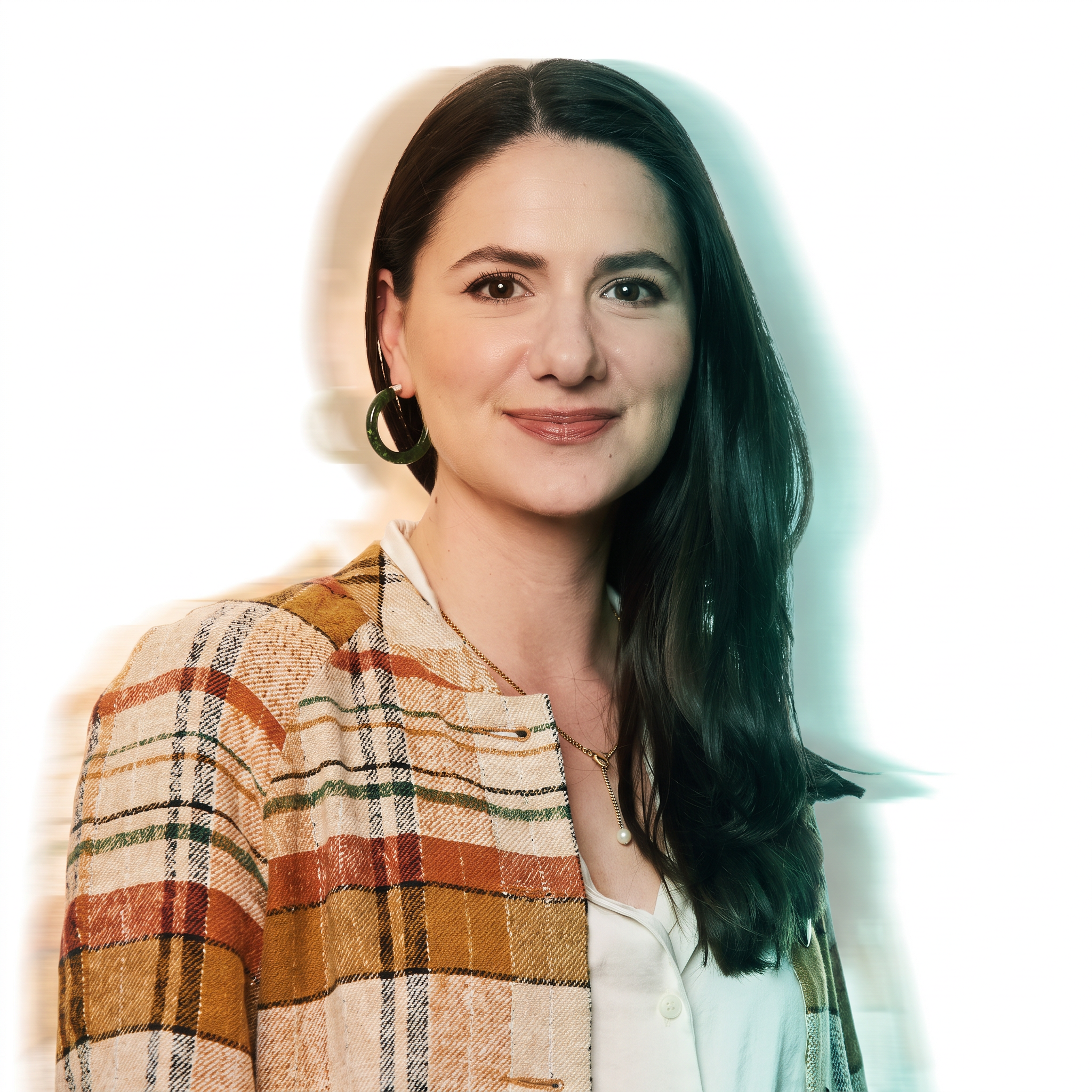 A woman with long dark hair and hoop earrings smiles while wearing a plaid jacket over a white top, set against a softly blurred light background.