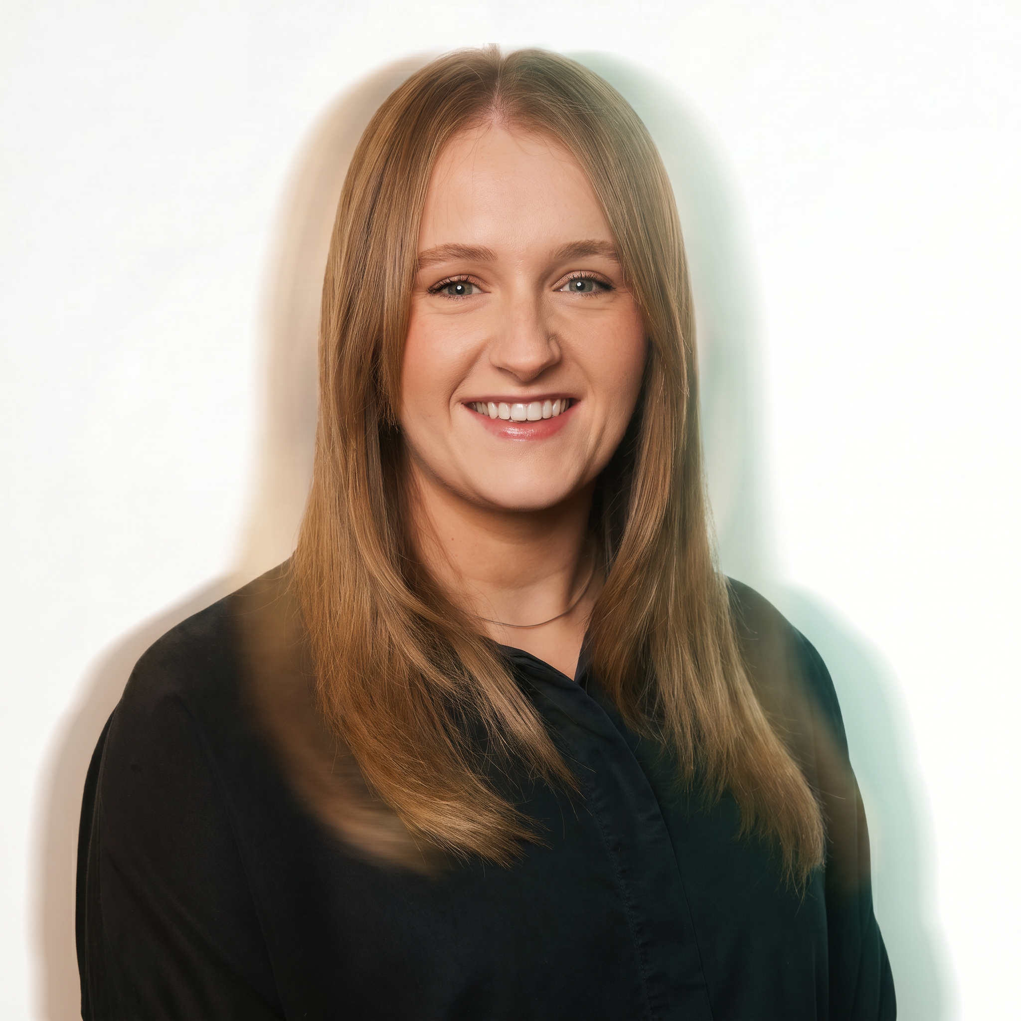 Headshot of a woman with long, straight hair, smiling and wearing a black shirt against a light background.