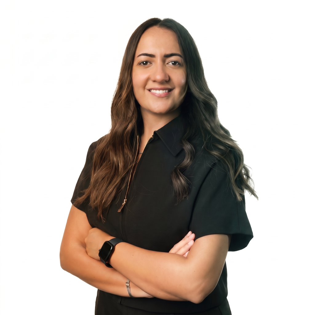 Woman with long, wavy hair, wearing a black shirt, smiling and standing with arms crossed against a white background.