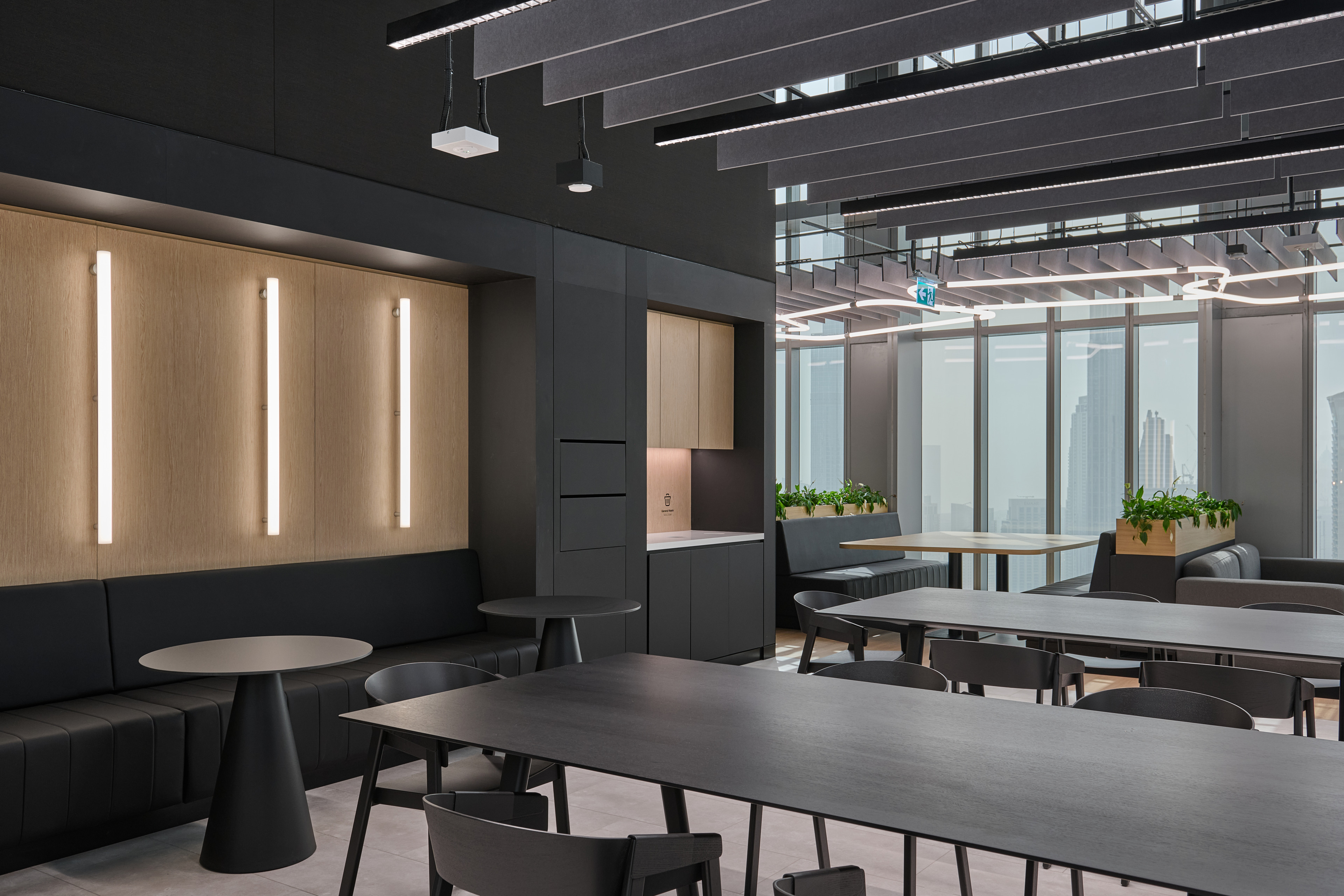 Modern office interior featuring black furniture, wooden accents, and large windows with city views.