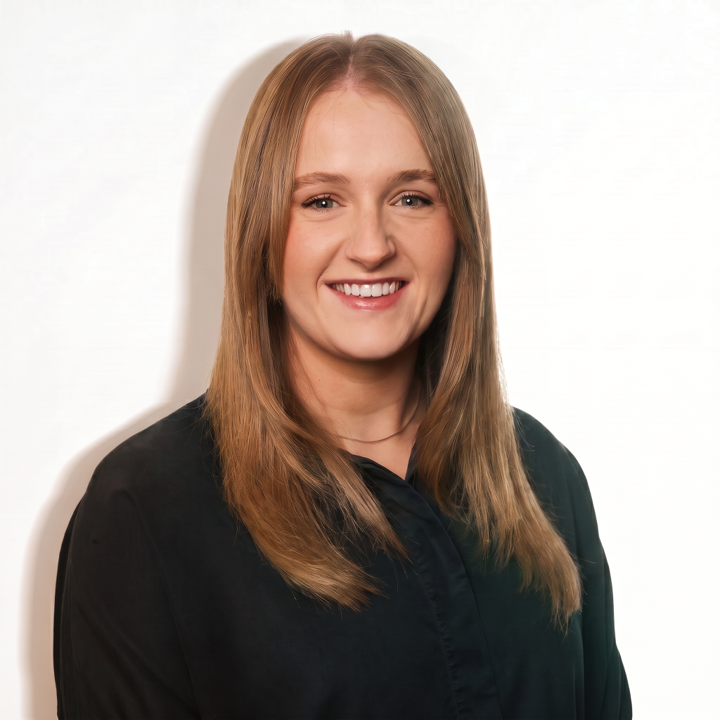 Sophie Grant smiling, wearing a black shirt, with long blonde hair against a light background.